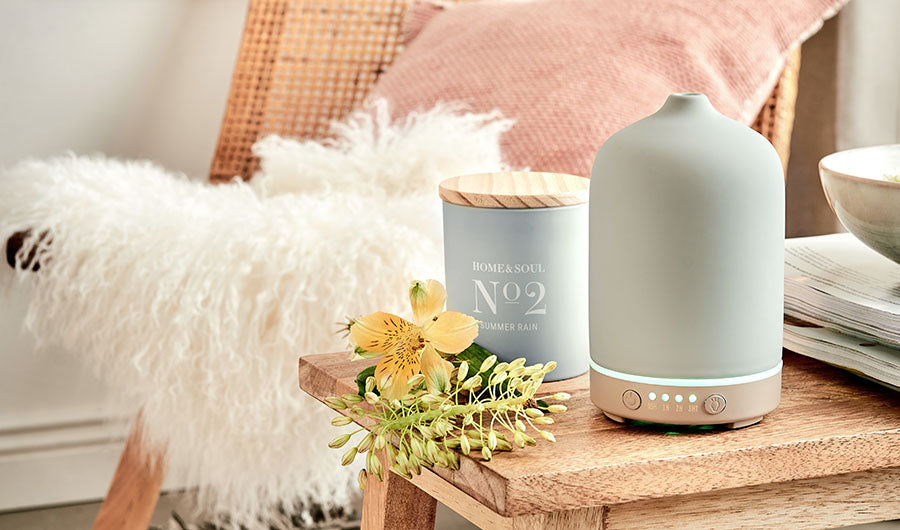 Ultraschalldiffusor und Home-and-Soul-Duftkerze auf Holztisch