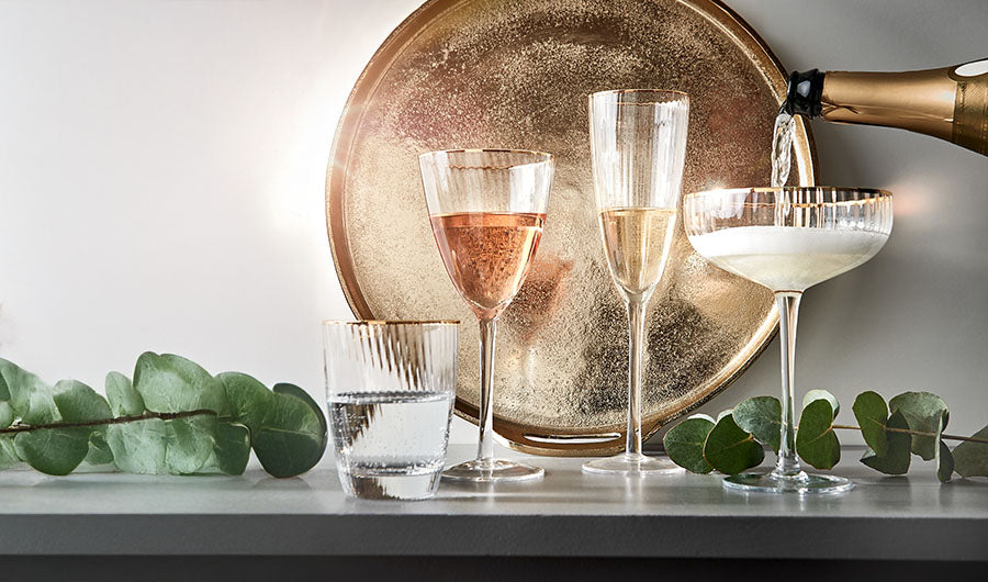 Sektgläser und Champagner-Coupe beim Einschenken von Champagner